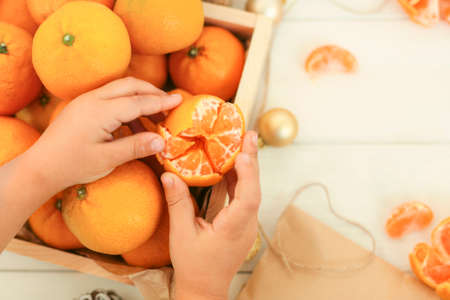 Hands hold, clean tangerine, decorate Christmas toys, a box of tangerines make a festive mood, space to copy.の写真素材