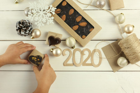 Christmas composition with a chocolate bar on a white wooden background with Christmas toys, balls,...
