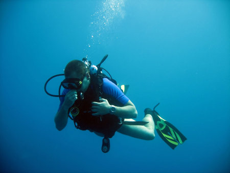 Diver, wreck in background equilising pressure in his mask and ears