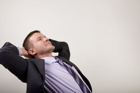 Business man reclines in his chair suggesting daydreaming, relaxation, thinking, planning, etc.の写真素材