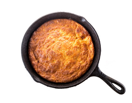 Home Style corn bread in a cast-iron skillet isolated on white.