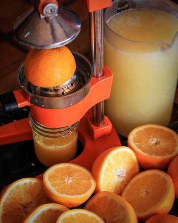 Squeezing fresh organic orange juice in the morning for breakfast using a manual citrus press.の写真素材