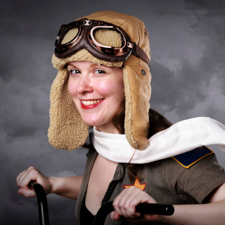Young woman dressed as an airplane pilot in vintage costume riding a bicycleの写真素材