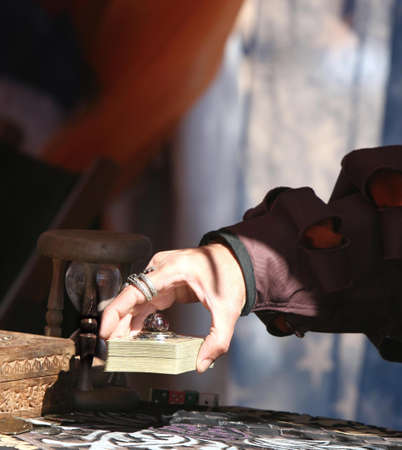 A hand set a stack of tarot cards down on a table. Shoot inside a tent.の写真素材
