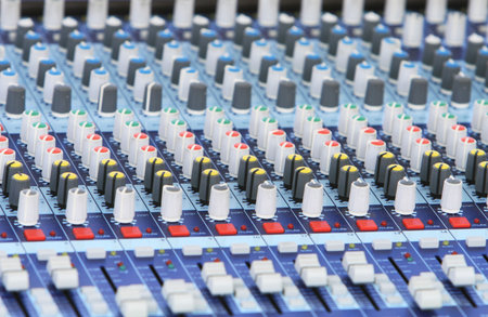 A audio mixer board. Spot focus on the center knobs.