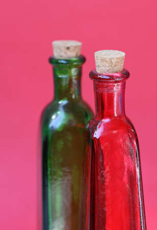 Emtpy red and green glass bottles with corks in the tops. Shot against a red backgroundの写真素材
