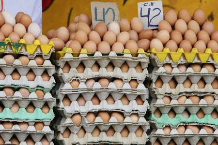 Stacks of fresh chicken eggs for sale in an outdoor marketplaceの写真素材