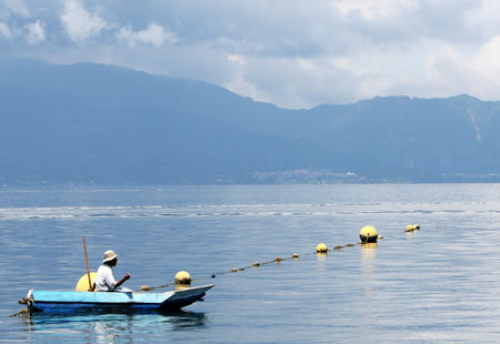 A fisherman floating in a small boatの写真素材