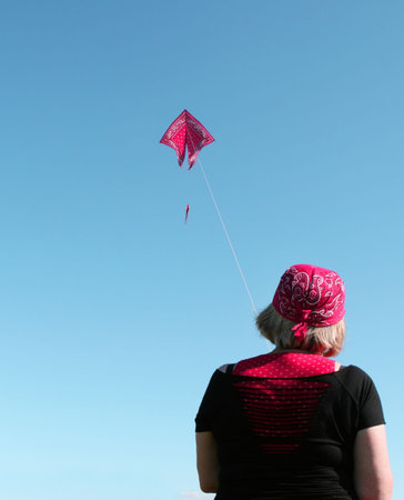 A woman in a bandana flies a kite of the same styleの写真素材