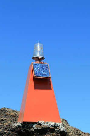 A bright orange beacon with solar panel warns ships of rocks and aids navigationの写真素材