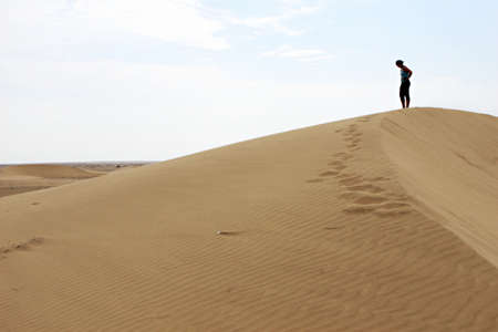 A woman walks along the ridge of a sand dune in the vast Peruvian desertの写真素材