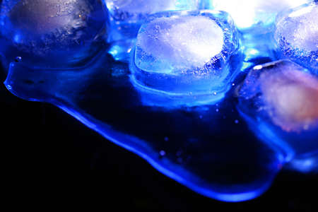Ice melting on a dark background. With blue lightの写真素材