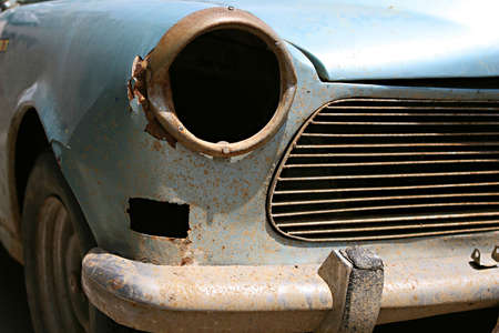 The front grill and headlight of an old car in need of restoration and repairsの写真素材