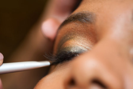 A young Indian woman has eye make-up applied at a salon