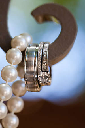A close-up shot of beautiful wedding rings hanging with pearlsの写真素材