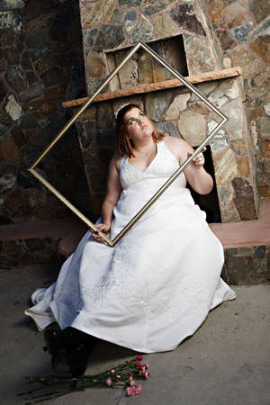 A beautiful plus size bride with green eye make-up posing in her wedding dressの写真素材