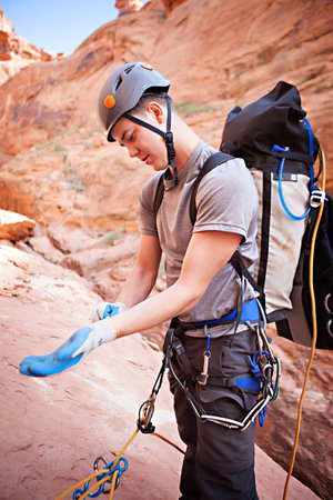 A young man prepares to rappel into a technical canyon in northern Arizona, USA