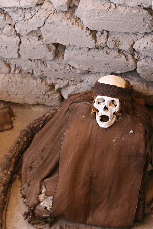This pre-incan mummy is preserved by the dry desert air with hair intact. Skulls and bones in Chauchilla, an ancient cemetery in the desert of Nazca, Peru. On the left is hair wrapped all the way around the body.の写真素材