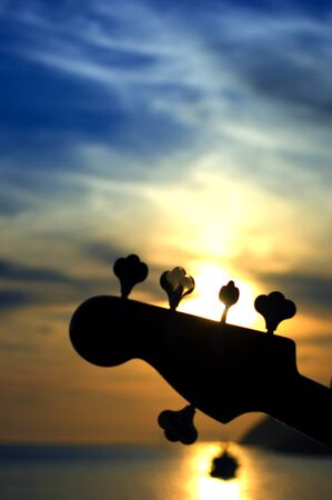 Bass guitar play in the dusk on the red sky and seaの写真素材