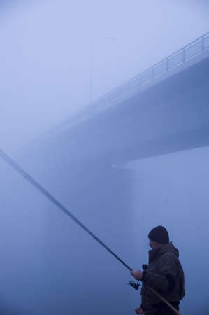 Fishing below the bridge in the fogの写真素材