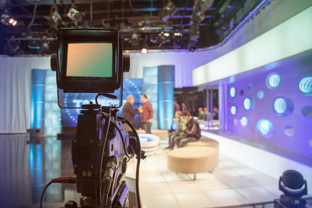 Television studio with camera and lights - recording TV show. Shallow depth of field - focus on cameraのeditorial素材