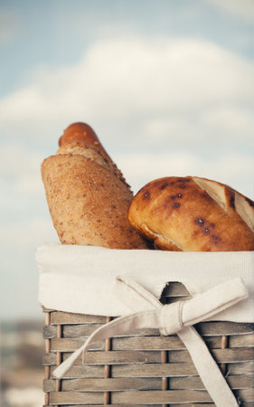 Various kinds of fresh tasty bread in wicker basket. Shallow depth of field, vintage style.