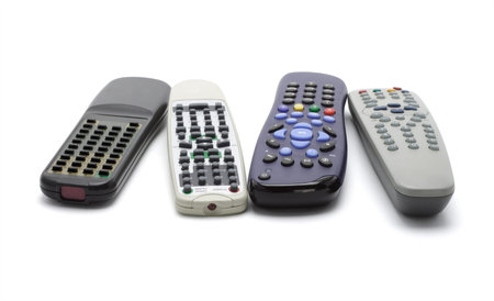 Assortment of wireless remote controllers arranged on white background