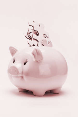 Conceptual image of jigsaw puzzle pieces inserted into piggy bank -  financial disarrayの写真素材
