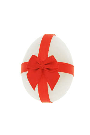 Semi precious stone in the shape of Easter egg decorated with red ribbon on white backgroundの写真素材