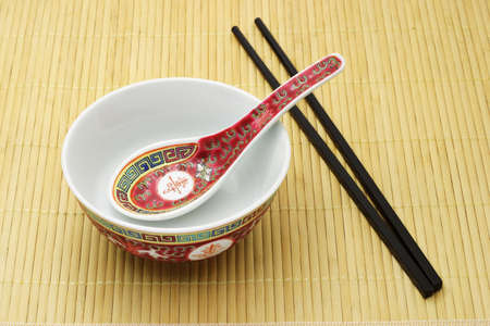 Chinese traditional bowl, spoon and chopsticks arranged on bamboo matの写真素材