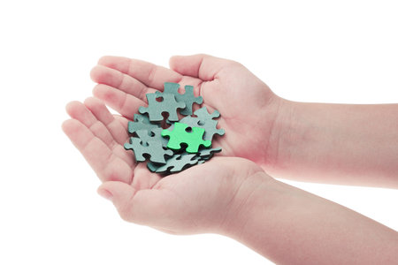 Pieces of jigsaw puzzle in boy's hands and one is highlighted