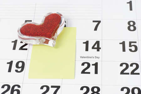 Heart shape glass paper weight and note paper on calendar page showing Febraury 14 Valentine's Dayの写真素材
