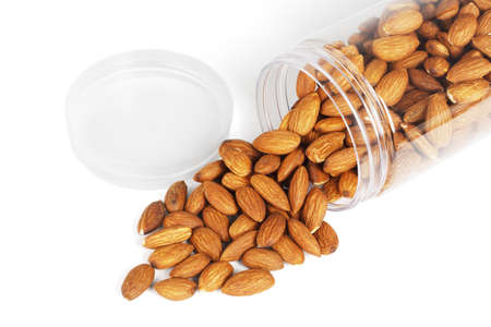 Almond Nuts Spilled Out From Plastic Container on White Backgroundの写真素材