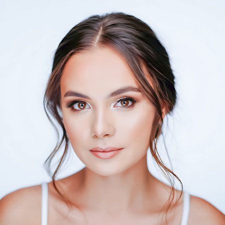 Close-up portrait of a young woman with dark hair and glamorous makeup. Her eyes are accentuated with dark eyeshadow and shimmering gold highlights.の素材