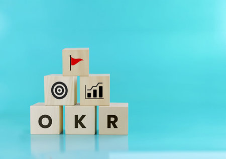 Wooden blocks with the word OKR and a target on a blue backgroundの写真素材
