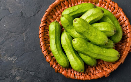 Fresh green chayote in a basket on a black background.の素材