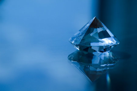 Brilliant blue diamond on a blue background. Shallow depth of field.