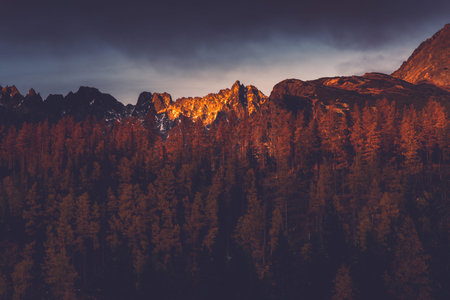 Last sun light hits high mountains peak at sunset.