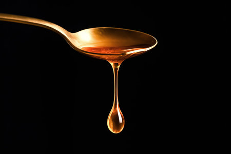 Honey dripping from a spoon on a black background. Healthy food.の素材