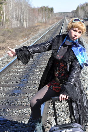 funny pictures, jokes, hitchhiking on the railroad, blonde woman with a suitcase catches a passing train as the car hitchhiking, a woman standing with arms raisedの写真素材