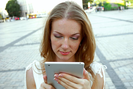 Pretty young  woman  using tablet pc outdoors on urban backgroundの写真素材