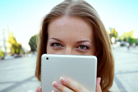 woman hiding her face behind tablet computerの写真素材