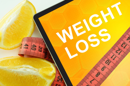 Tablet with words weight loss and measuring tapeの写真素材