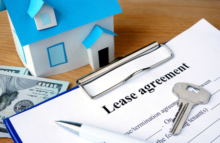 Lease agreement document with dollars and home model.の写真素材