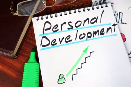 Notepad with personal development on a wooden surface.の写真素材