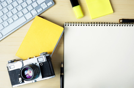 Open note with stickers, marker, keyboard and old camera on a table. Mock-up photo.の写真素材