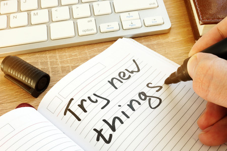 Man writing: try new things in a note.の写真素材