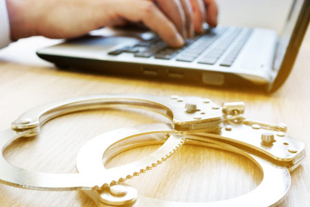 Computer crime. Man with laptop and handcuffs. Investigation concept.