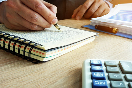 Businessman writing financial results in the book. Bookkeeping concept.