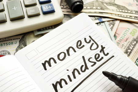 Money mindset handwritten in a note and dollar banknotes.